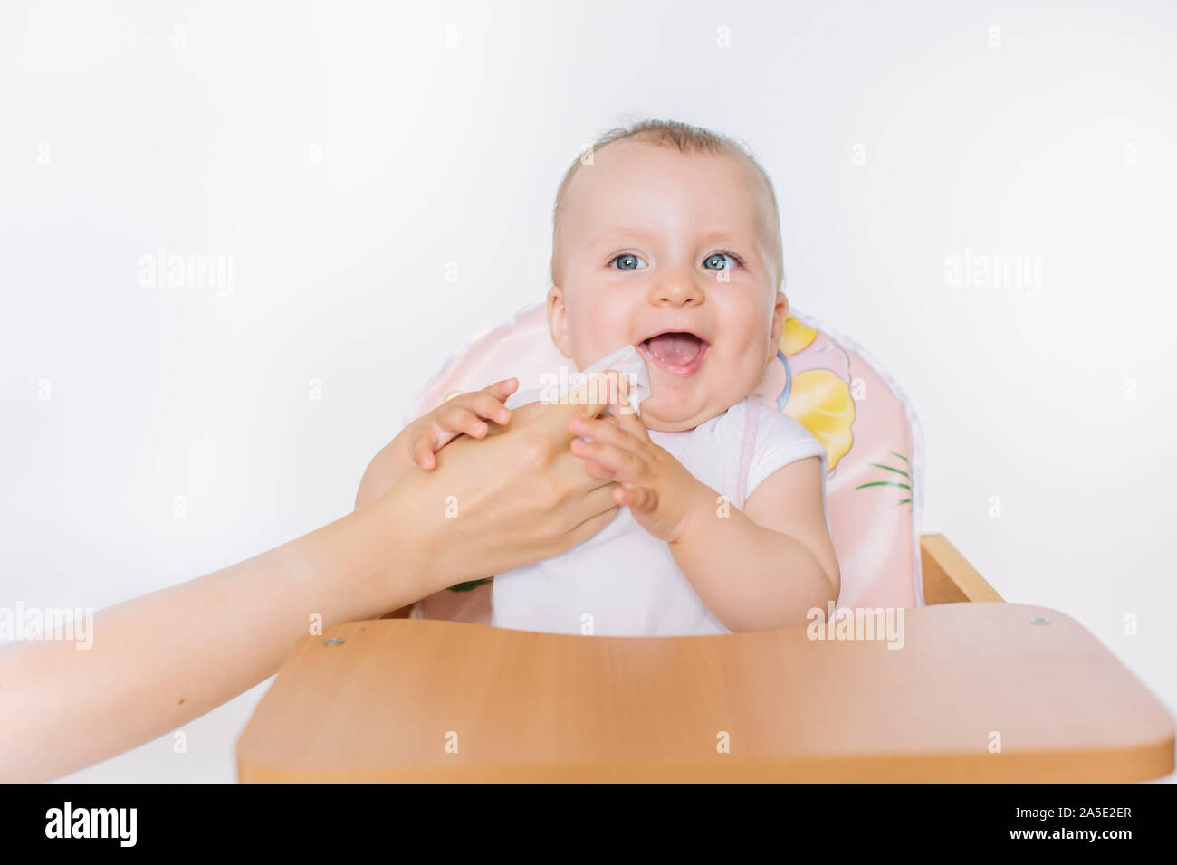 mom in the kitchen wipe the mouth of her baby after meal Stock Photo