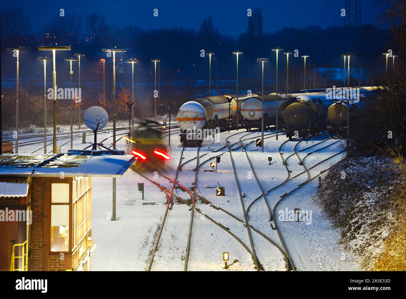 Winter night shot of an industrial railroad yard with a moving train. Stock Photo