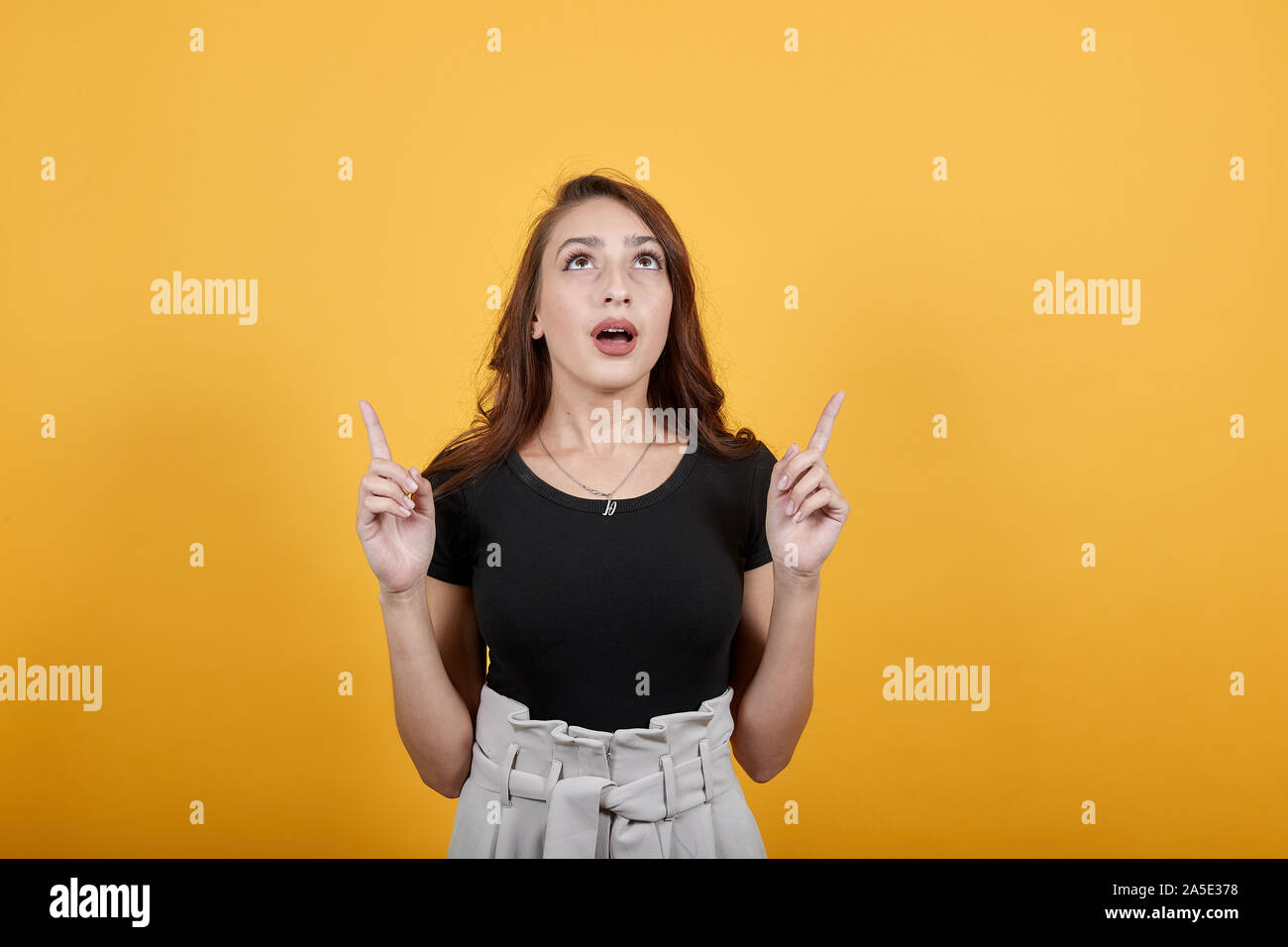 Beautiful religious girl trusting in god as she points her fingers up. Stock Photo