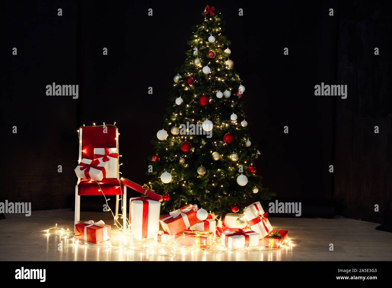 Christmas lights with Christmas tree and gifts on a black background ...