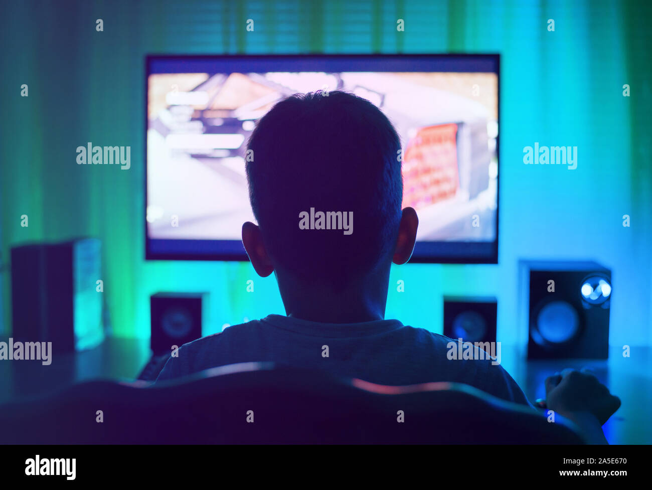 Boy as anonymous, using a computer or playing a game. View from back. Stock Photo