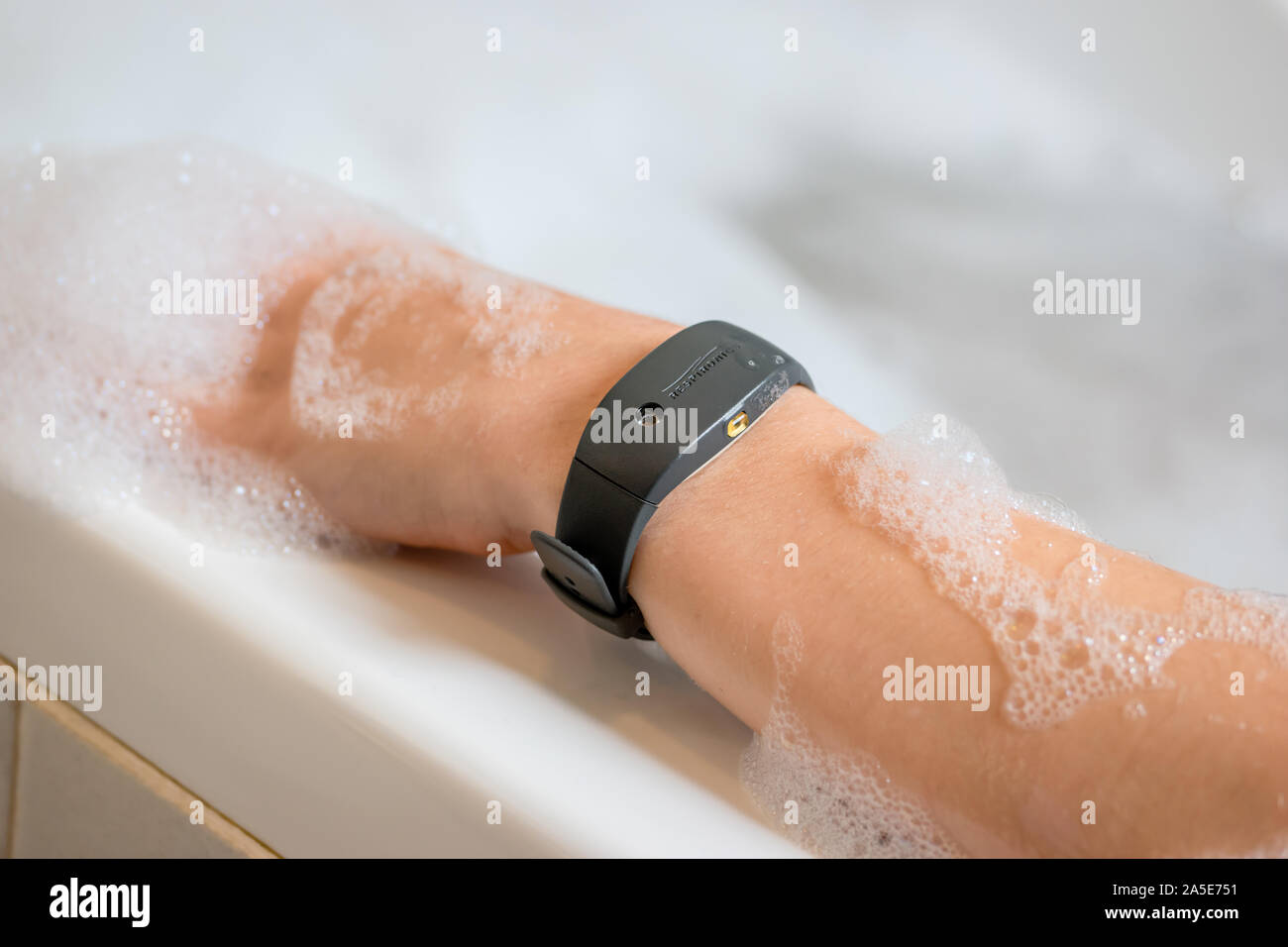 An arm in the bath wearing a Philips Respironics Actiwatch, a durable