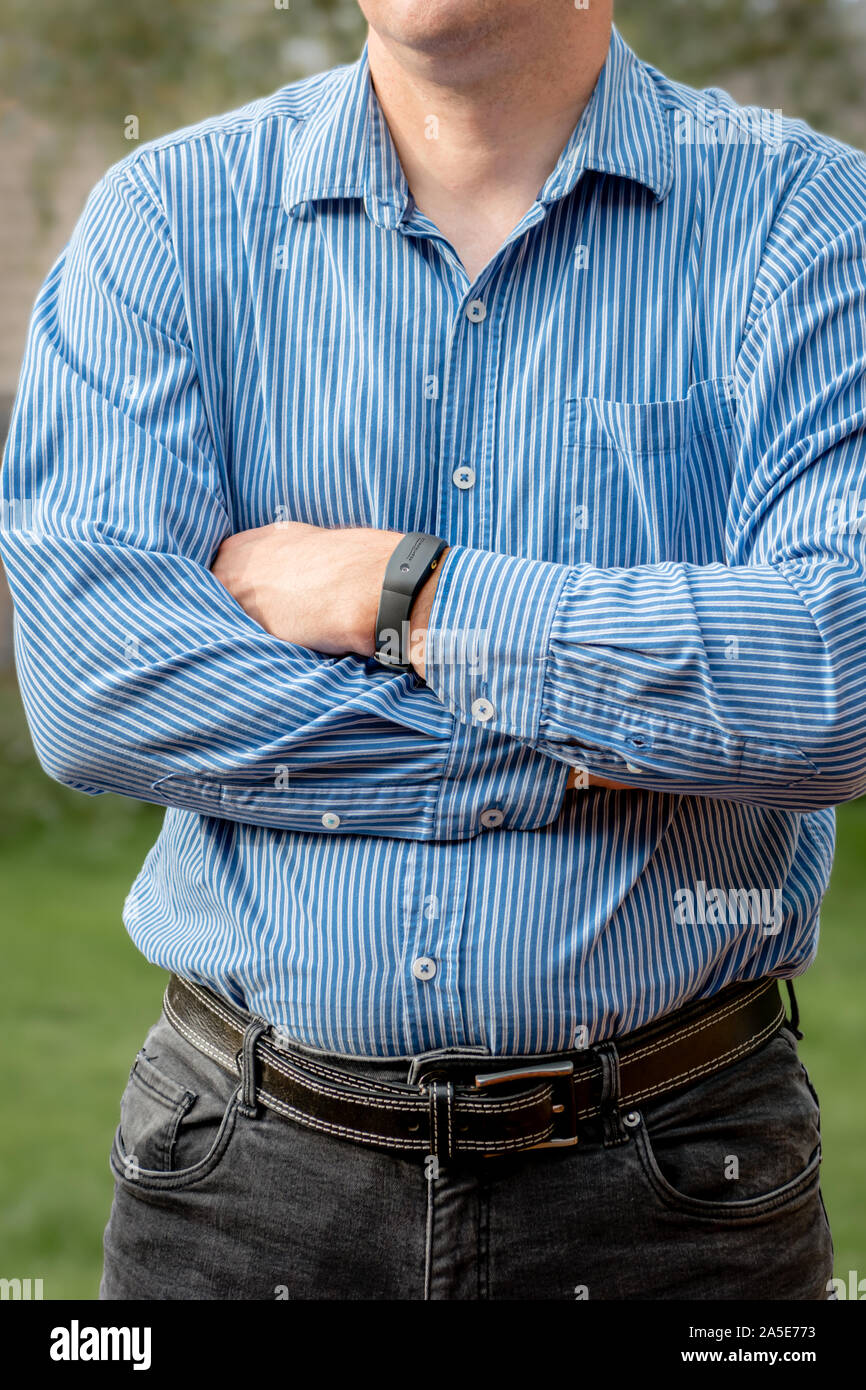 A man in a shirt wearing a Philips Respironics Actiwatch, a clinical research-grade tracker watch for insomnia, sleep studies and activity monitoring Stock Photo