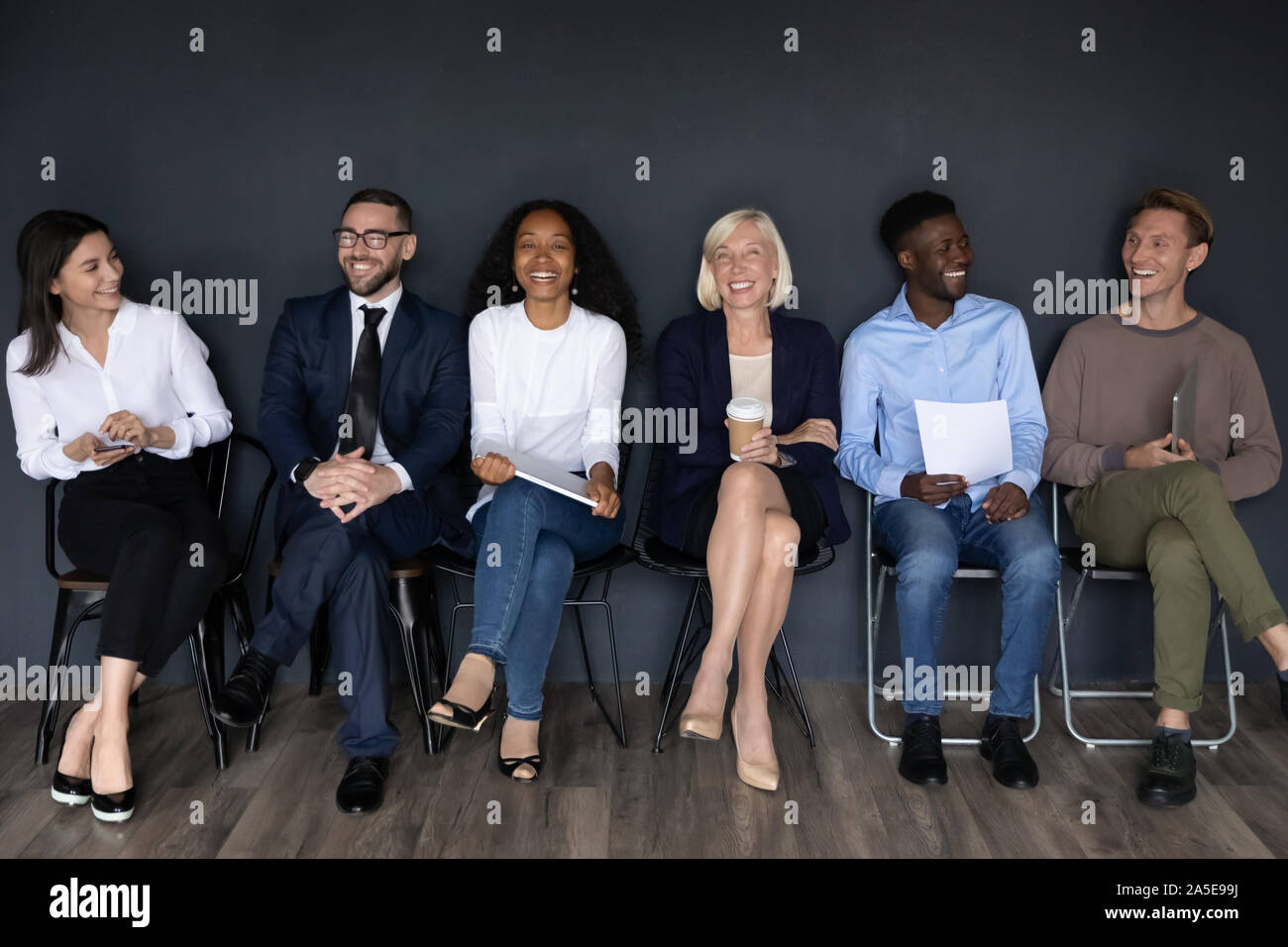 Happy multiracial businesspeople group sit on chairs laughing, human resource Stock Photo