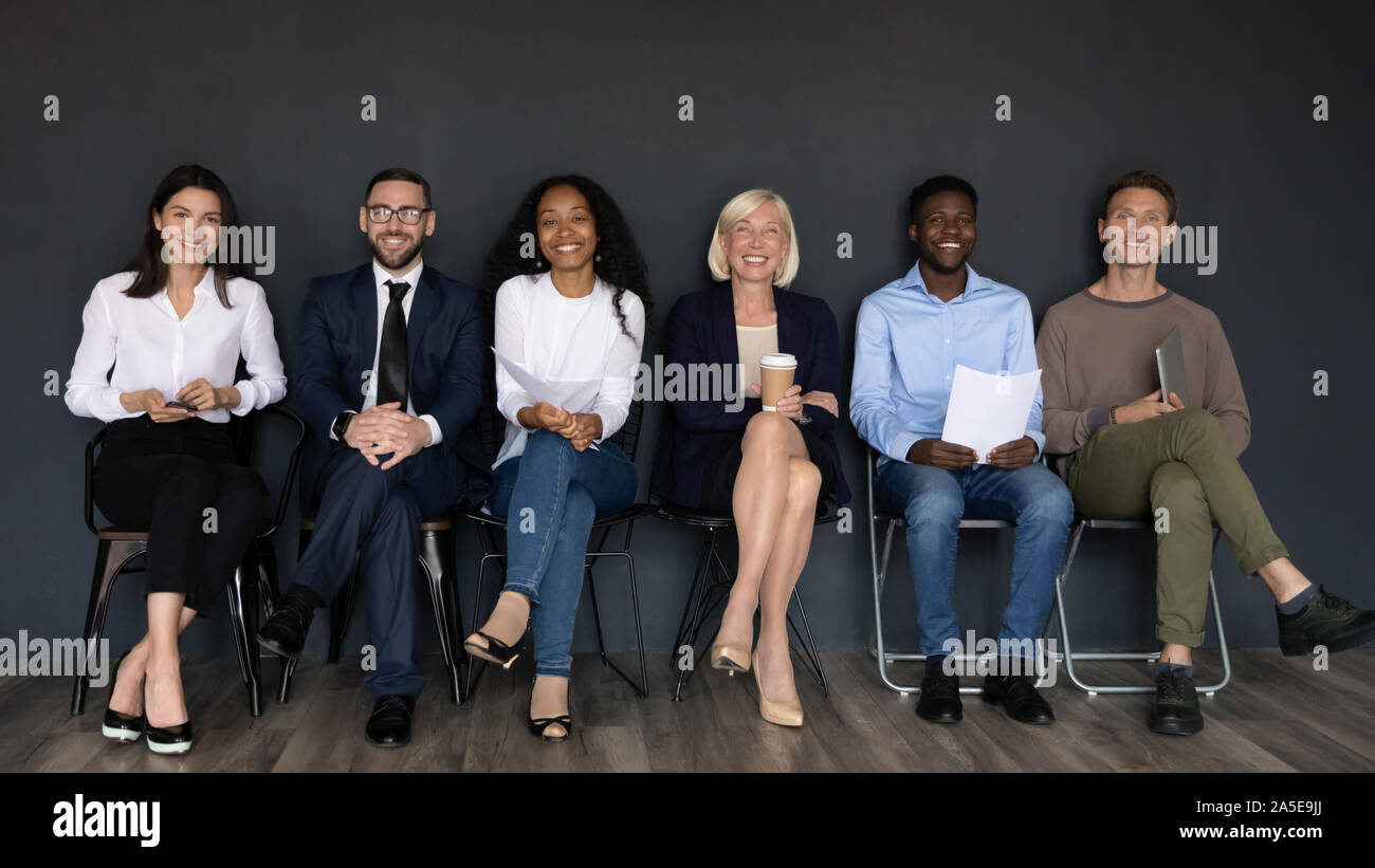 Smiling multiethnic professionals sit on chairs looking at camera Stock Photo