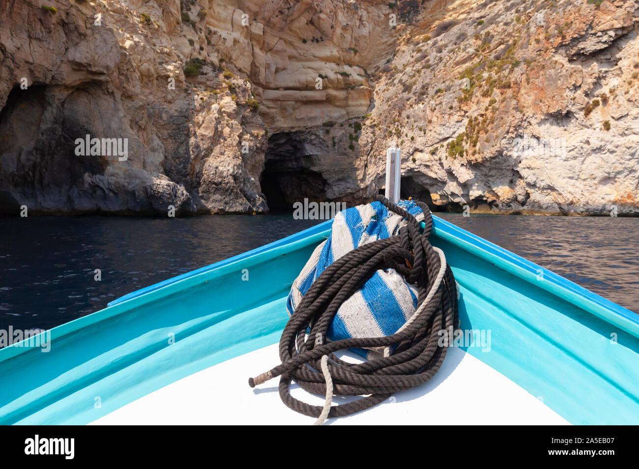 Bow of a small boat with nautical rope near rocky coast at summer sunny day. Blue cave, Malta Stock Photo