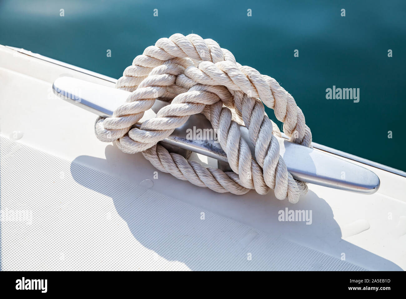 https://c8.alamy.com/comp/2A5EB1D/stainless-steel-boat-mooring-cleat-with-knotted-rope-mounted-on-white-yacht-deck-2A5EB1D.jpg