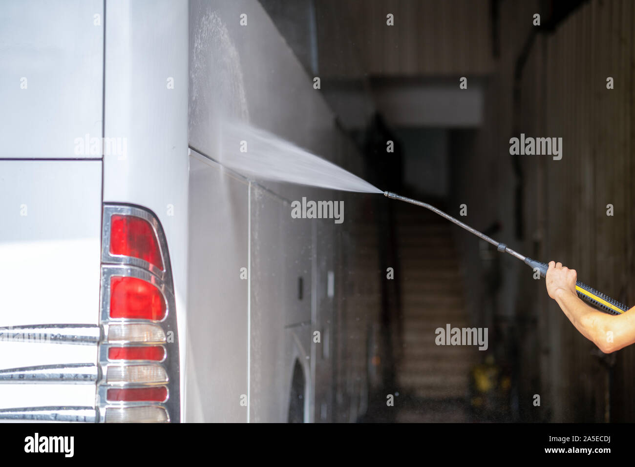 bus get washed from a washer with water jet in garage. Stock Photo