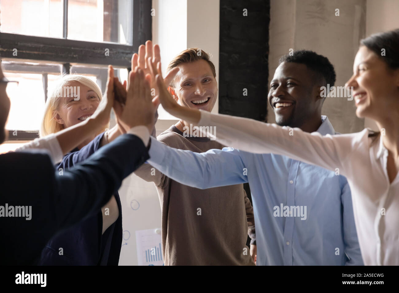 Motivated diverse professional team give high five together celebrate ...