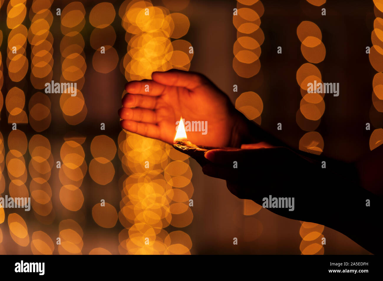 Young woman holding diya, clay oil lamp during Diwali festival. Concept for traditional diwali, holiday festive season background with copy space. Stock Photo