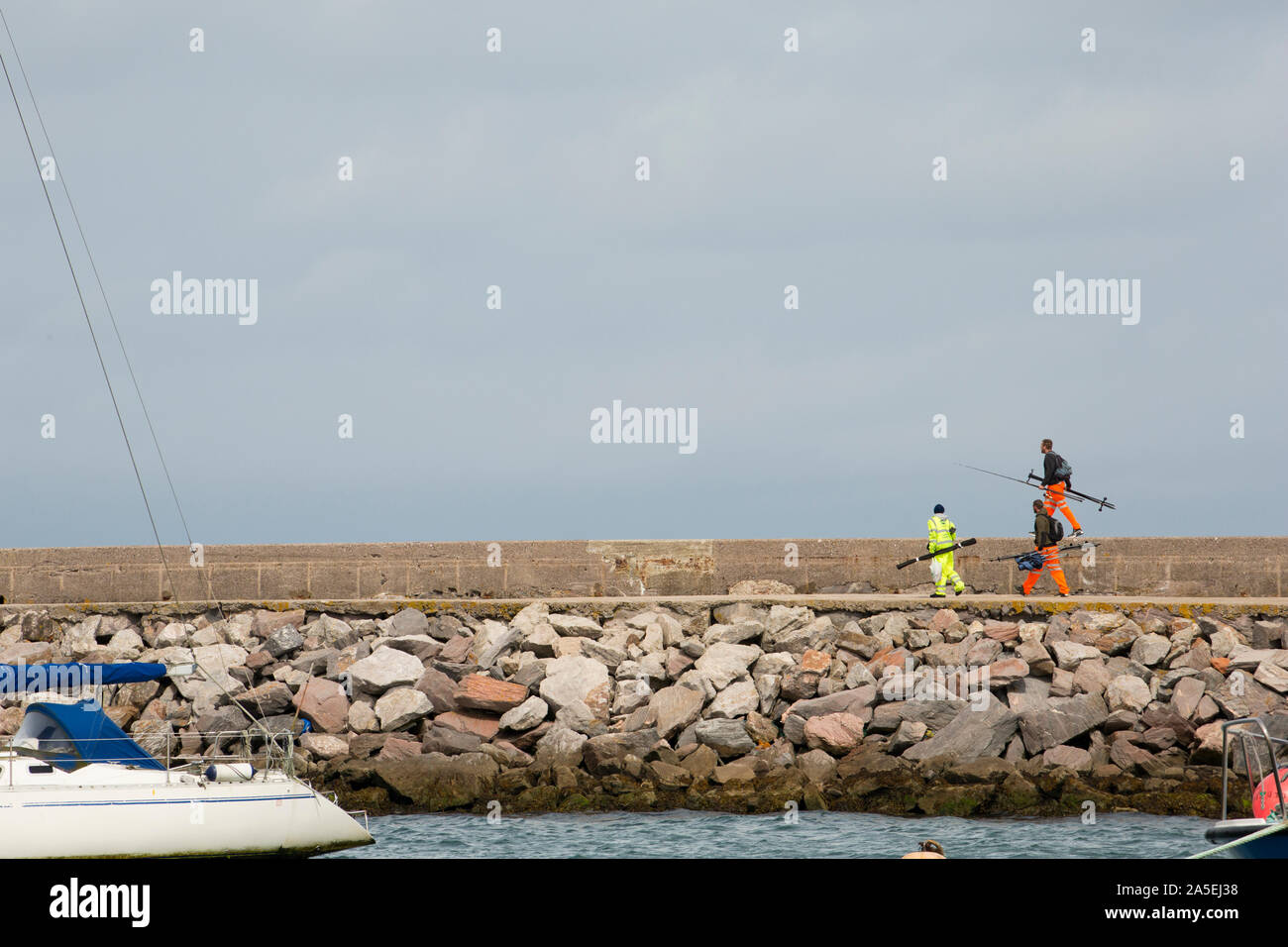 Sea anglers on their way to go fishing on Brixham Breakwater near the town of Brixham in Devon England UK GB Stock Photo