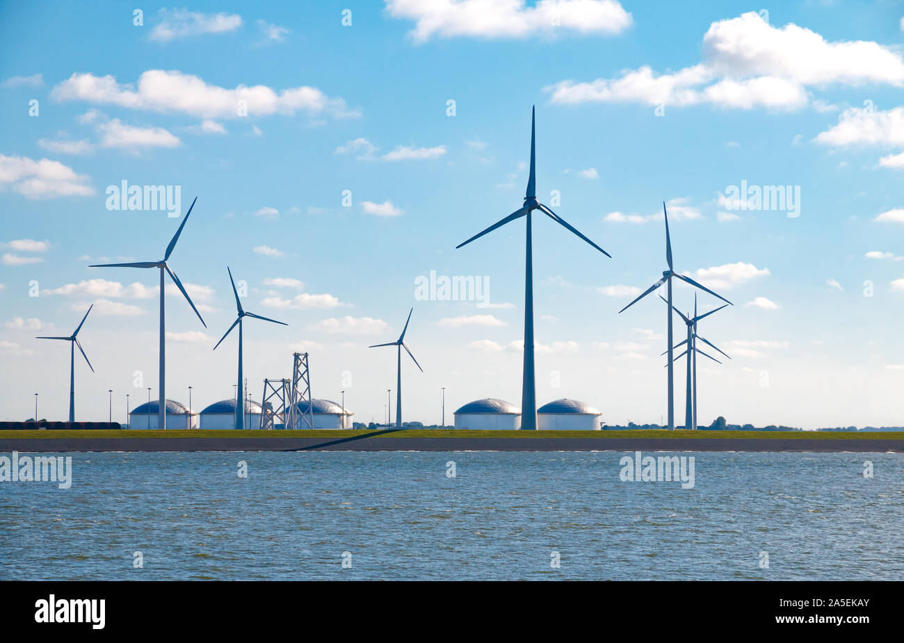 Contrast of an old and new source of energy: Wind turbines and oil storage tanks at the Eemshaven seaport in Groningen, Netherlands Stock Photo