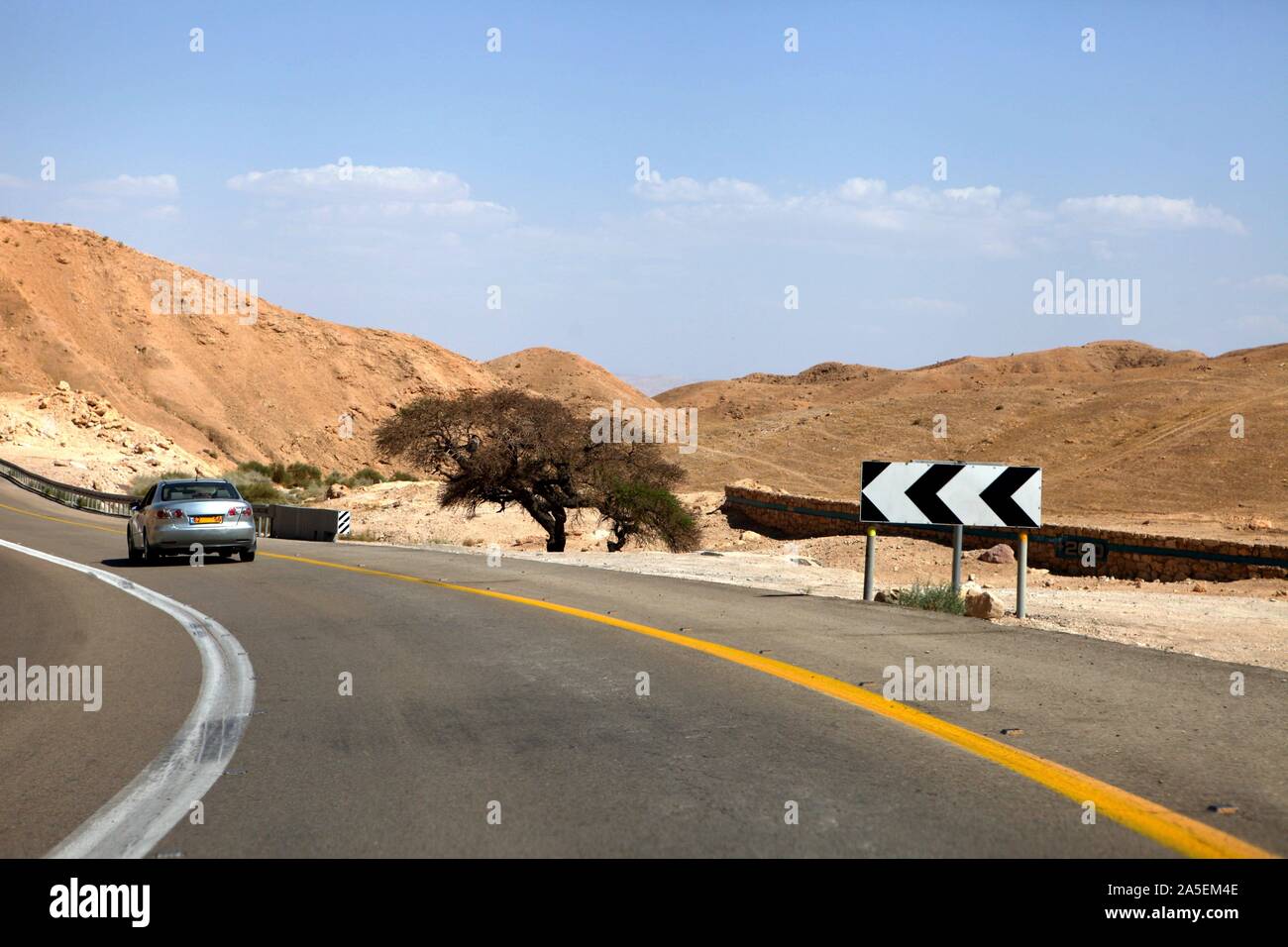 car on a highway that runs along the Dead Sea from one side and Edom Mountains at Arava Desert from the other in Israel. Stock Photo