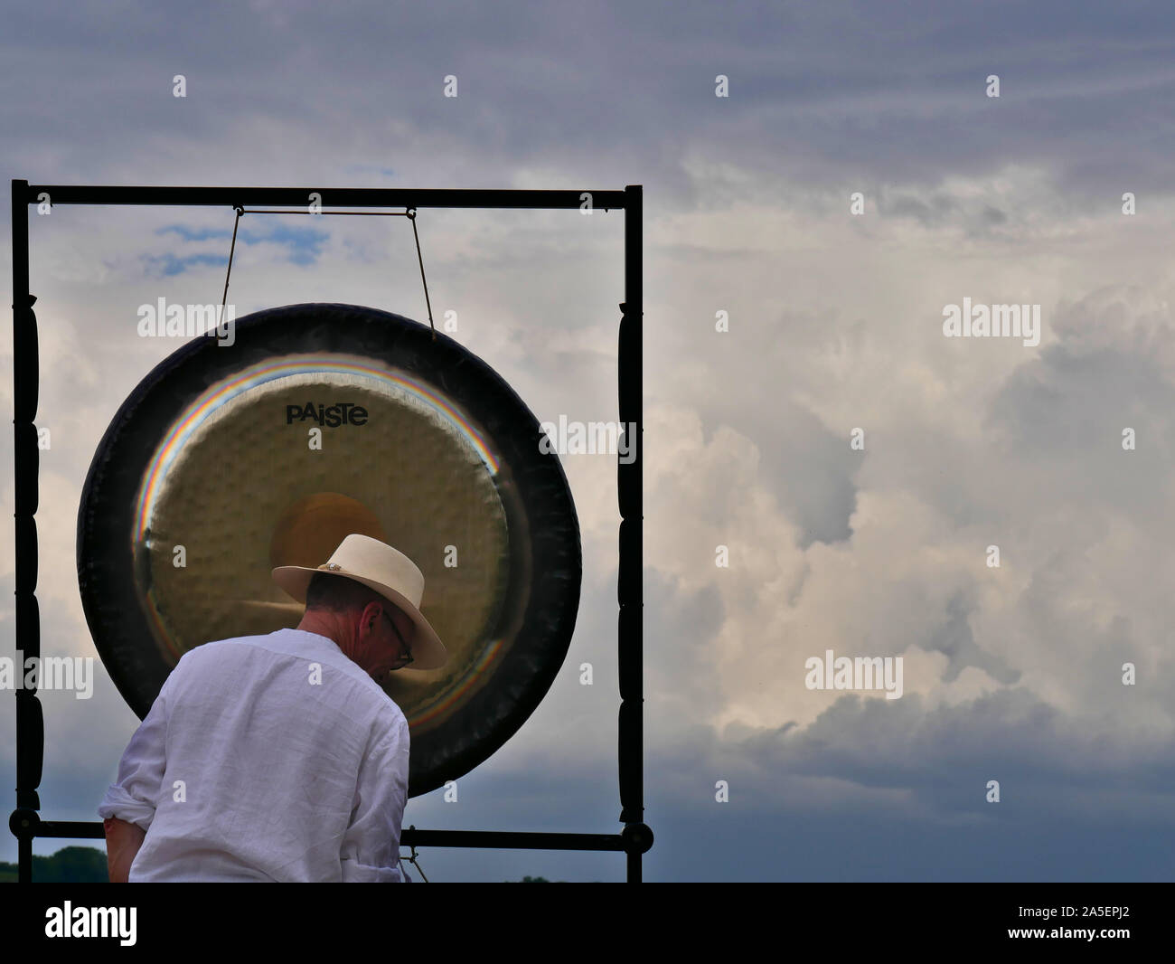 Man with white shirt and straw hat playing gong Stock Photo Alamy
