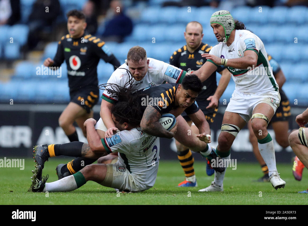 Wasps' Malakai Fekitoa is tackled by London Irish's Saia Fainga'a and Harry Elrington during the Gallagher Premiership match at the Ricoh Arena, Coventry. Stock Photo