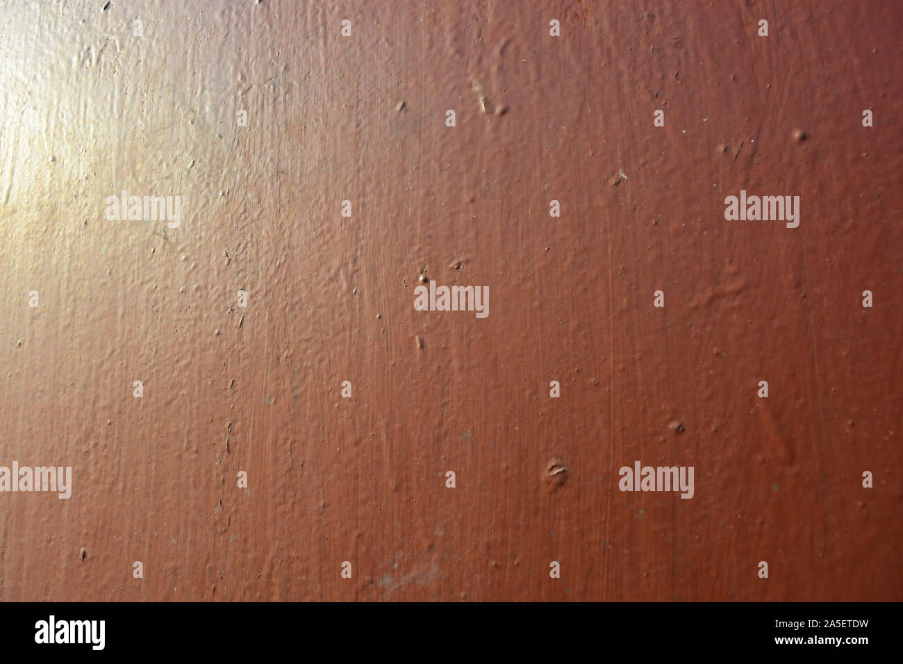 Old metal building sheet covered with brown paint with a golden tint in