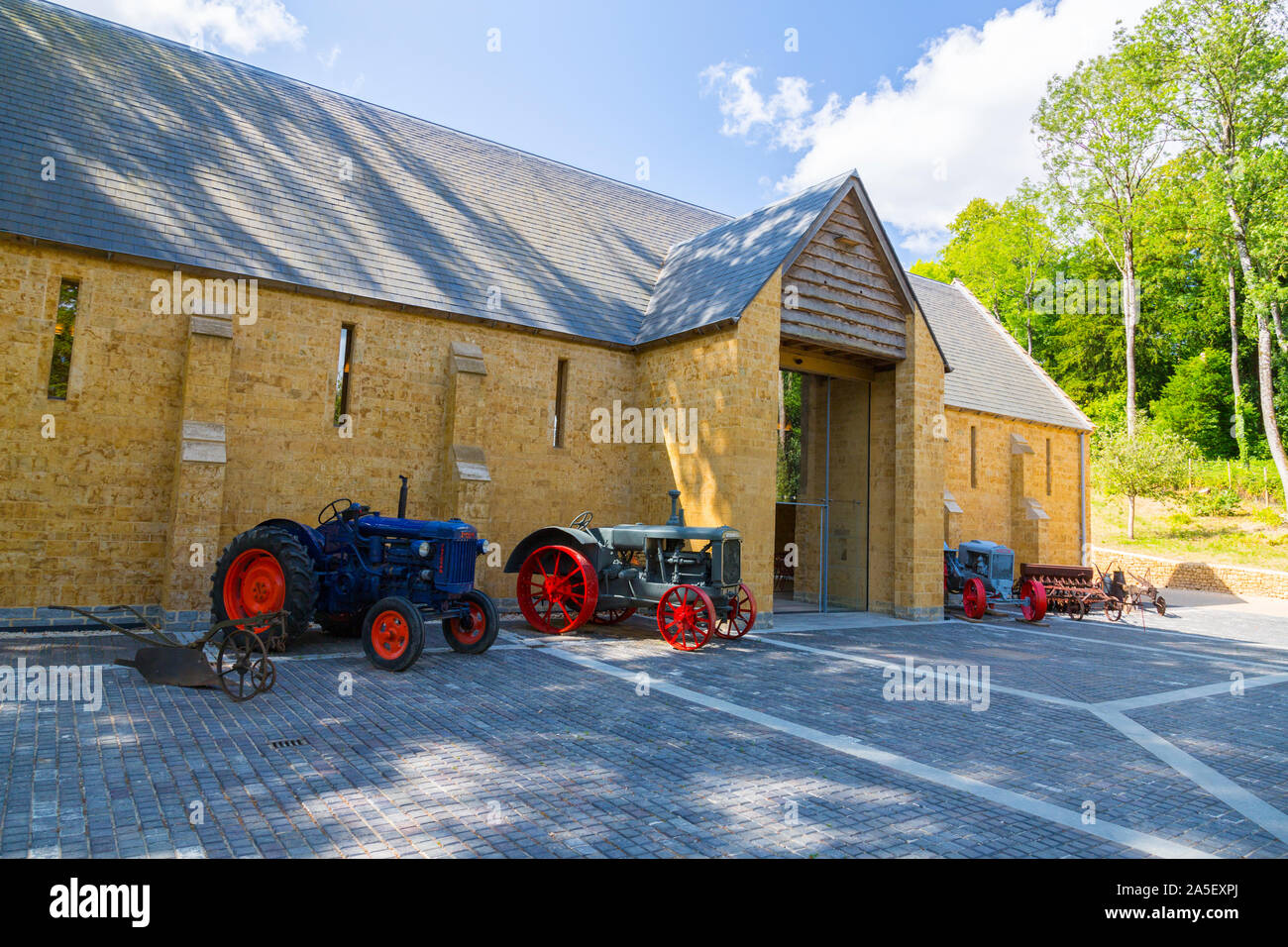 Vintage tractors and farm machinery outside the threshing barn at the newly restored 'The Newt in Somerset' garden and hotel, nr Bruton, England,UK Stock Photo
