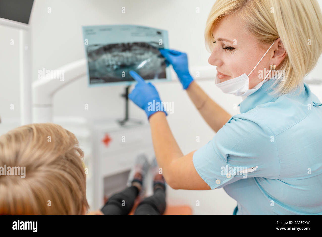 Smiling female dentist demonstrating an Xray film of jaws to her