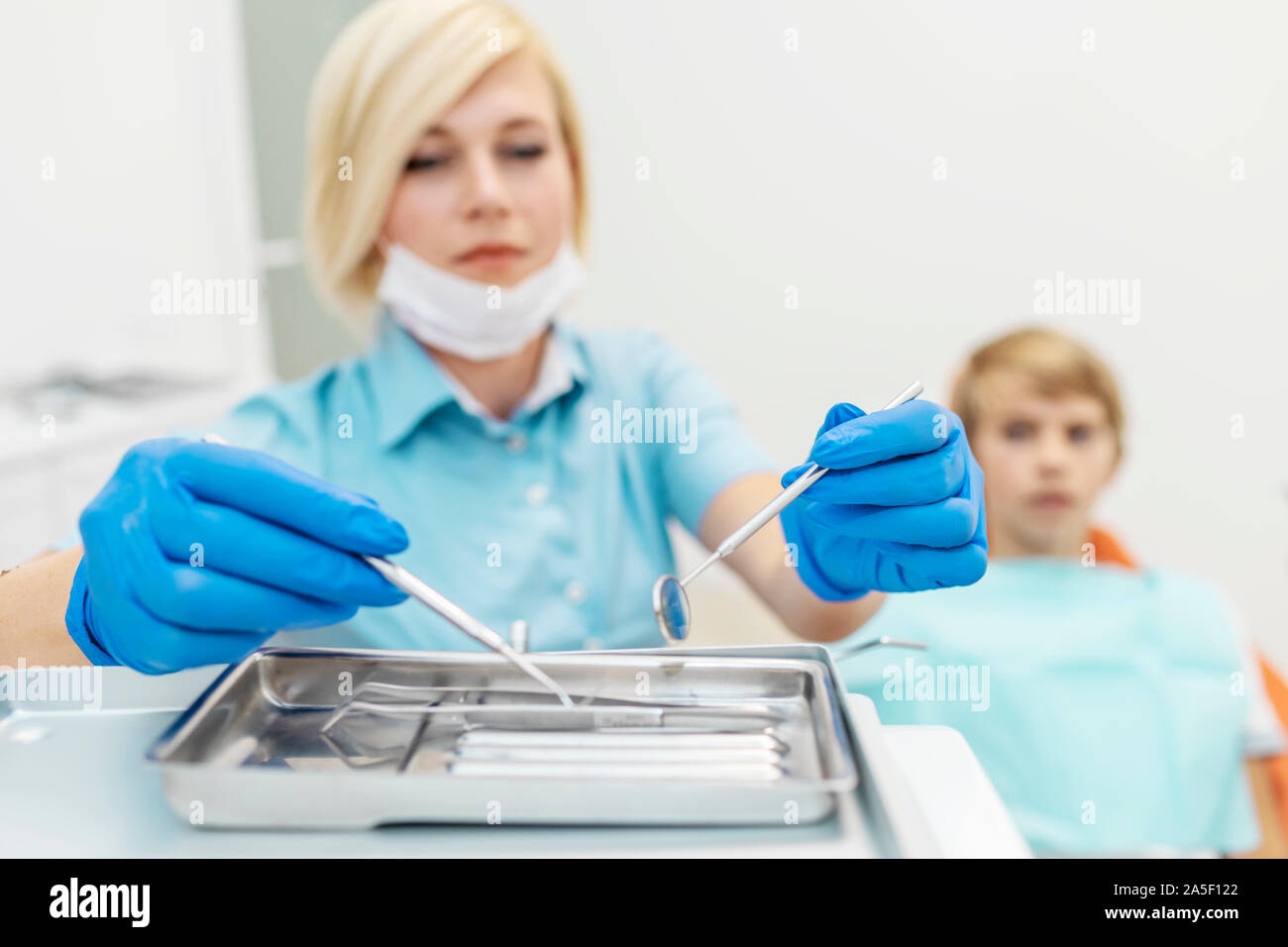 Teen patient watching female dentist picking the dental instruments Stock Photo