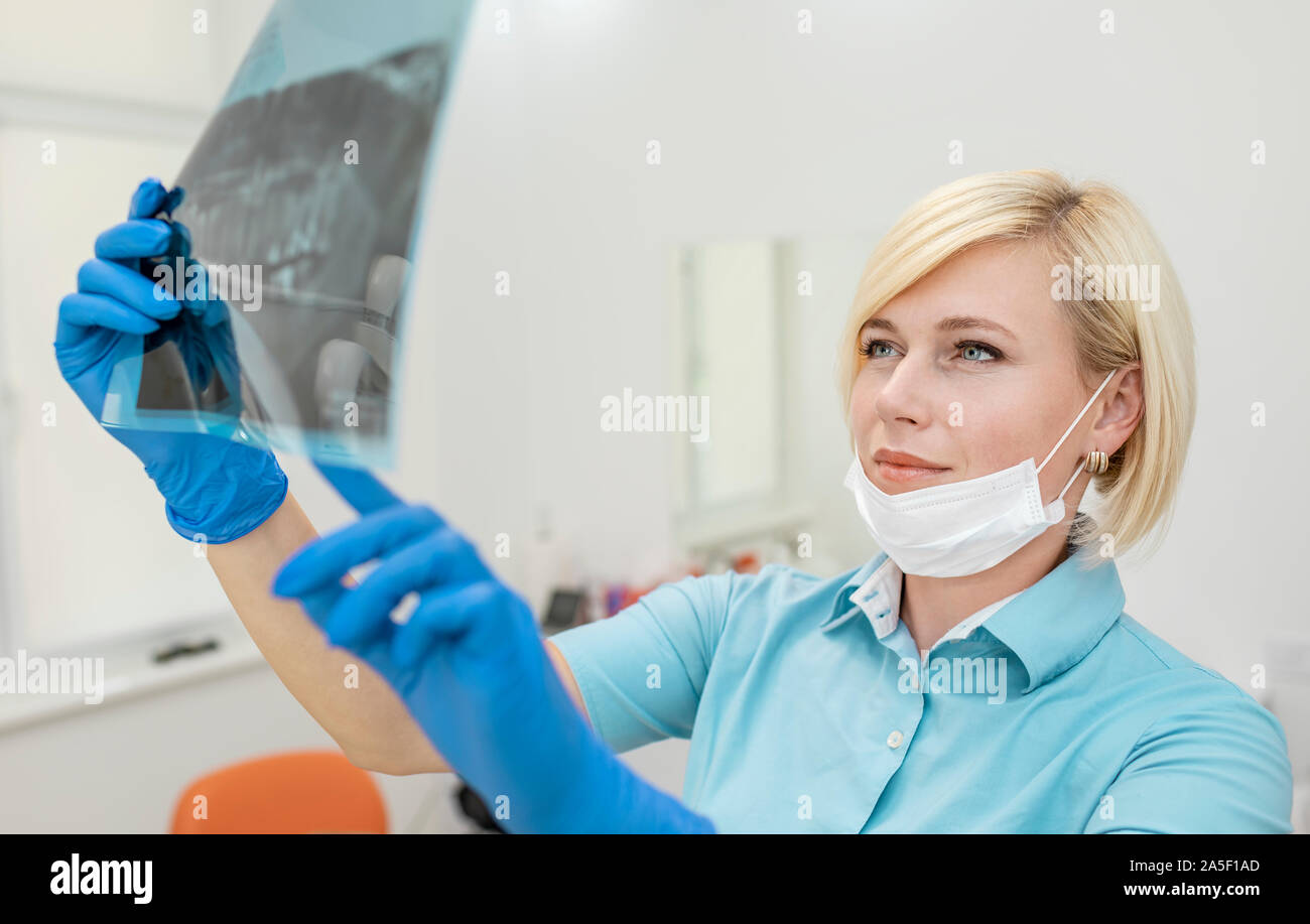 Concentrated blonde female dentist examining the teeth and jaws X-ray photography Stock Photo