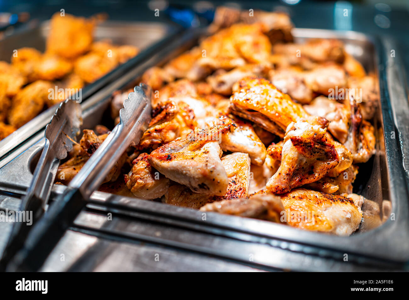 Roasted chicken wings buffet bar self serve with tongs in grocery store, restaurant or catering event with crisp skin and unhealthy food Stock Photo