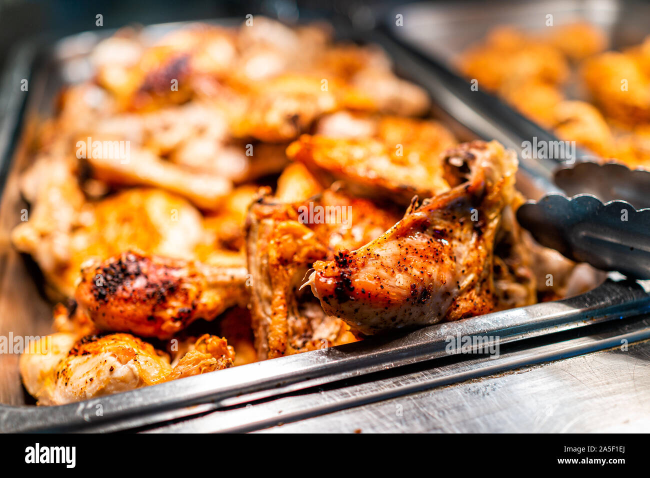 Roasted chicken thighs buffet bar self serve with tongs in grocery store, restaurant or catering event with crisp skin and unhealthy food Stock Photo