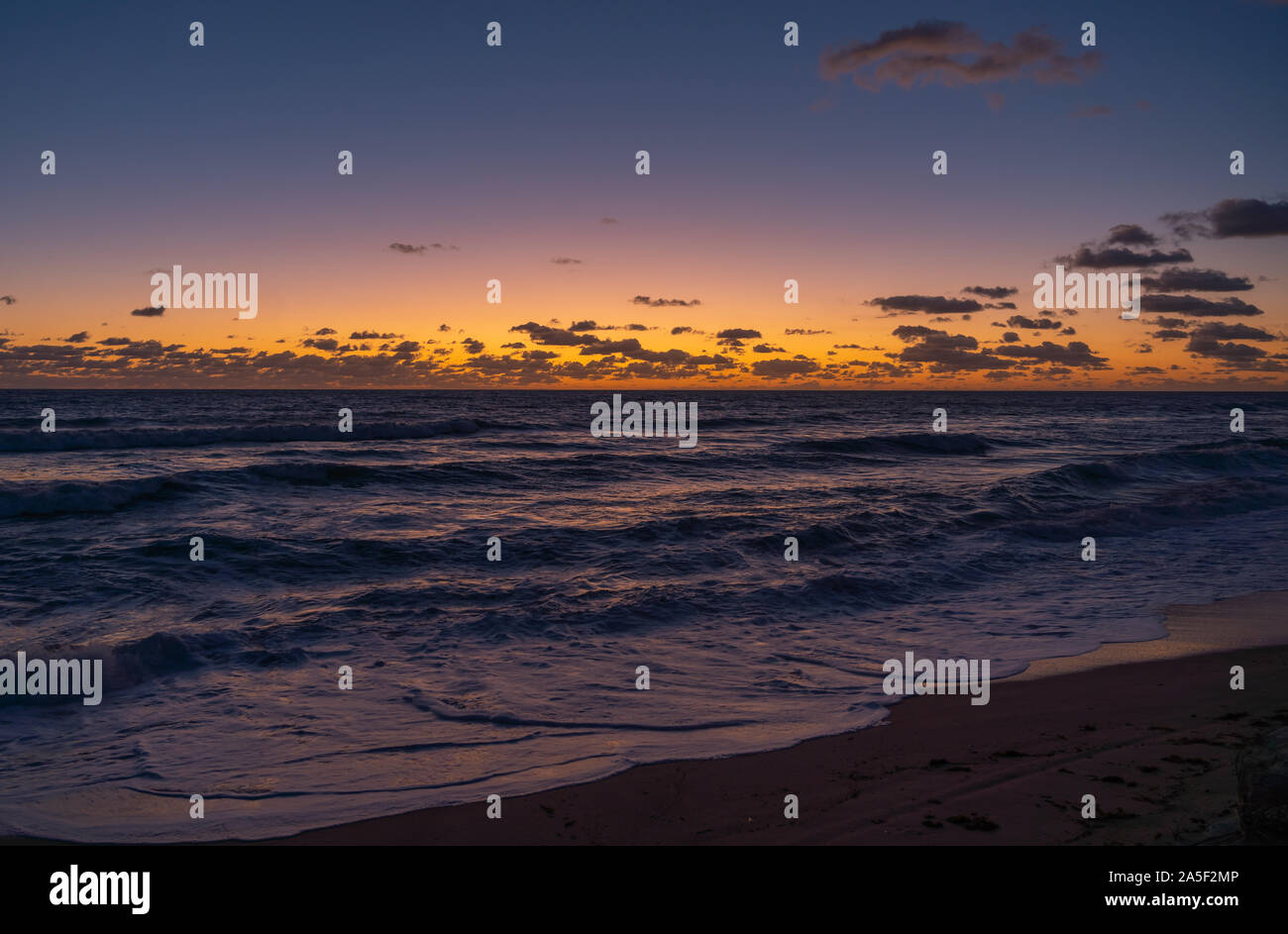 The sky glows brightly orange prior to the sunrise on the beach in Florida Stock Photo