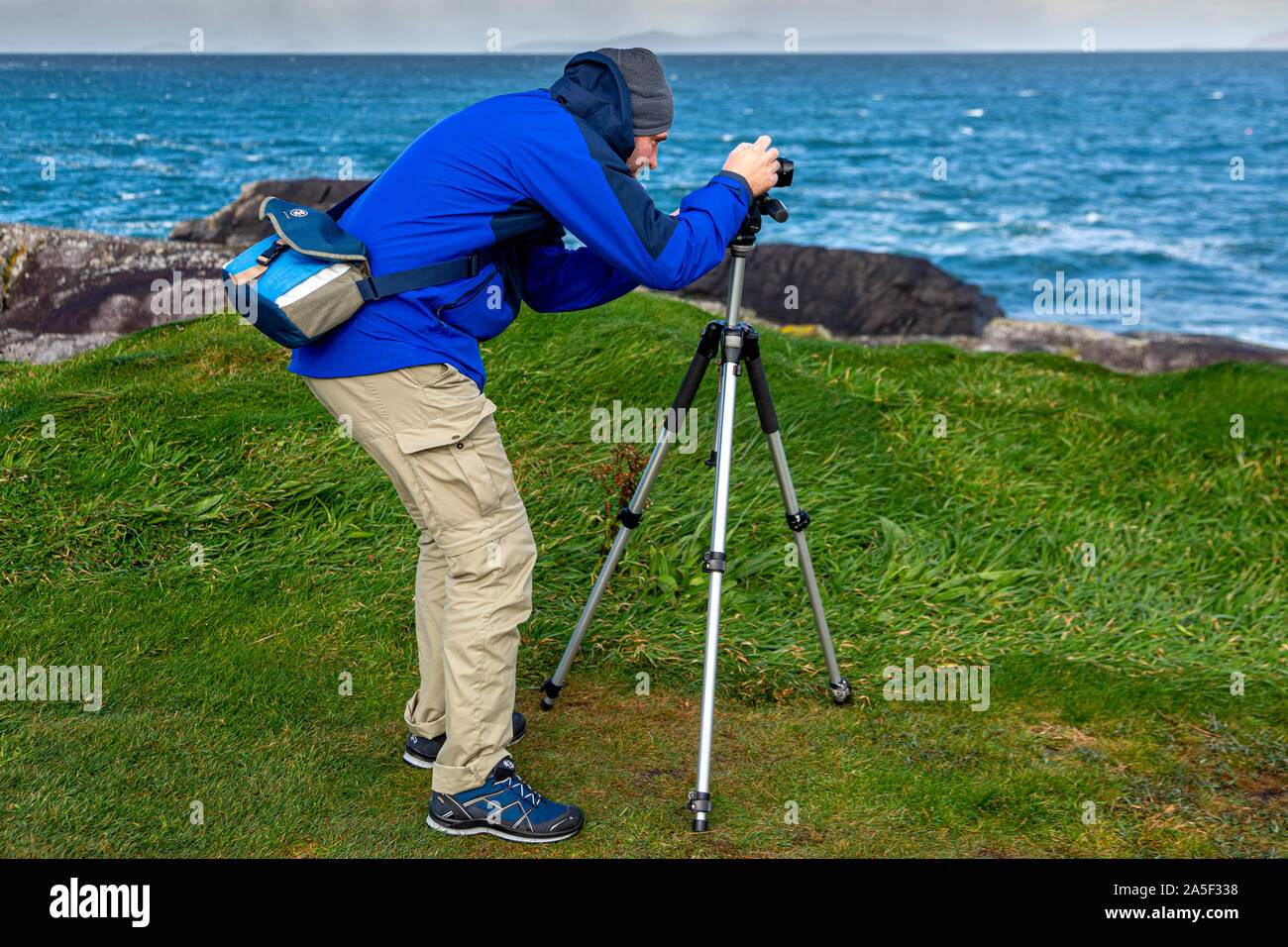 Young man photographing landscape with a camera and tripod Stock Photo