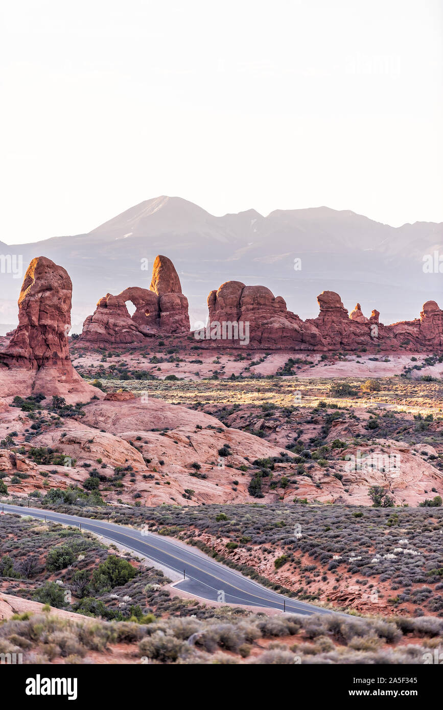 High angle vertical view of empty road leading to window arch in Arches National Park in Utah during morning sunrise with orange red pink rock color Stock Photo