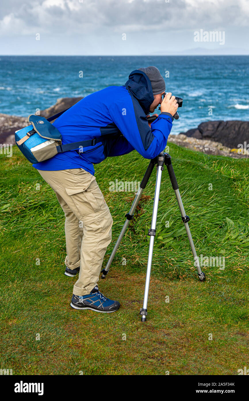 Young man photographing landscape with a camera and tripod Stock Photo