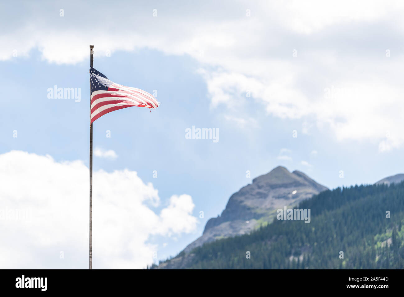 Flagpole on main street in Silverton, Colorado summer with American flag waving in the wind and mountain peak in summer and blue sky clouds Stock Photo