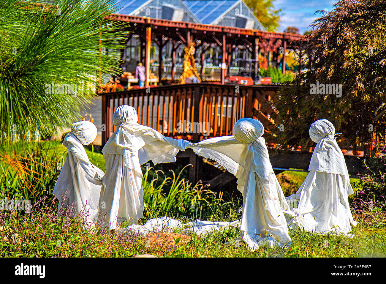 Local plant nursery's Halloween display of a group of playful ghosts in front of their business made out of white sheets. Stock Photo