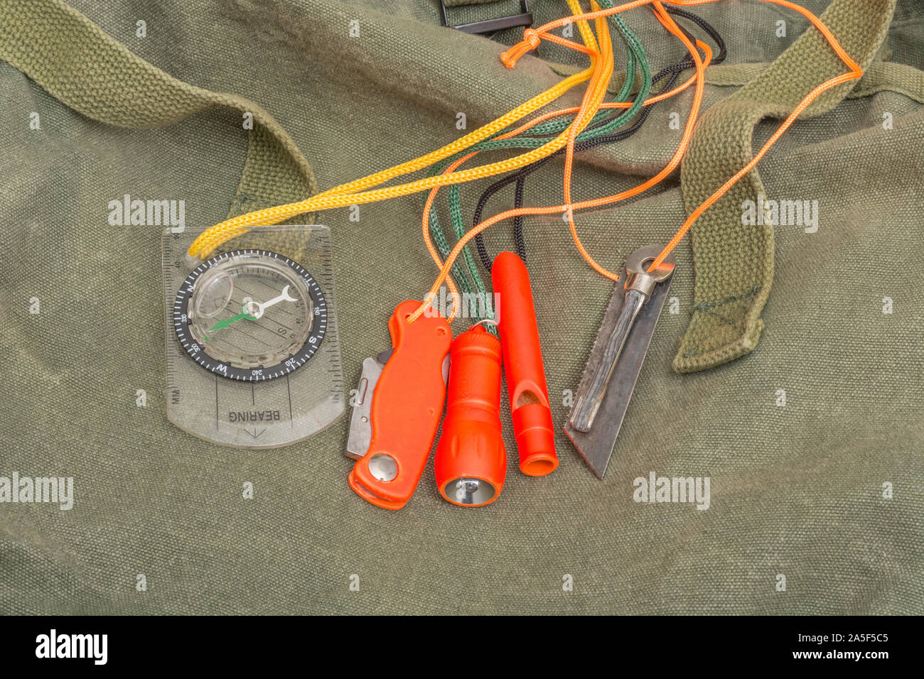 Survival skills & gear. High vis survival firelighter, survival whistle, high viz survival torch, high viz knife, survival compass, emergency kit. Stock Photo