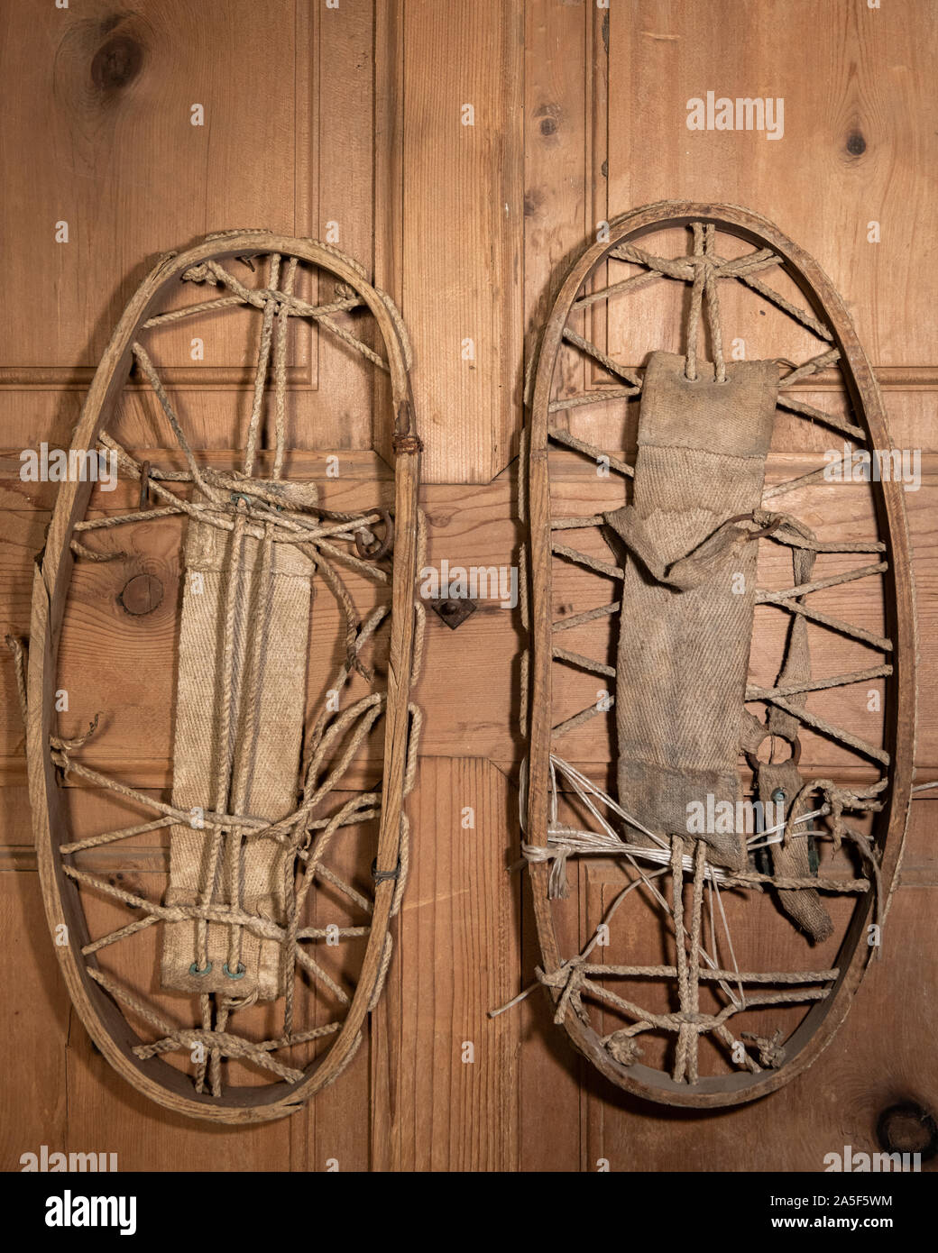 Closeup of a pair of very old snowshoes hanging on a wooden wall Stock Photo