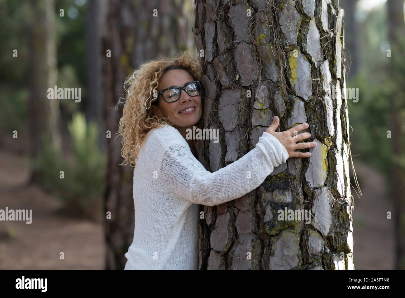 one woman hugging with close eyes a old tree on the forest - love and ...