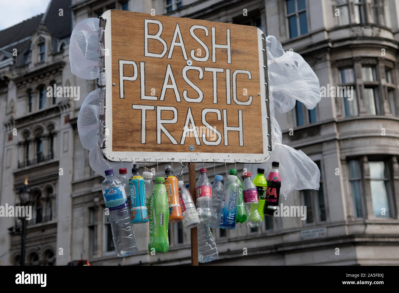 Plastic protest London UK 2019. Robert Unbranded demonstrates in Westminster,  holding up a Bash Plastic Trash poster sign, with one use plastic bottles and plastic bags hanging from it. England 2010s. HOMER SYKES Stock Photo
