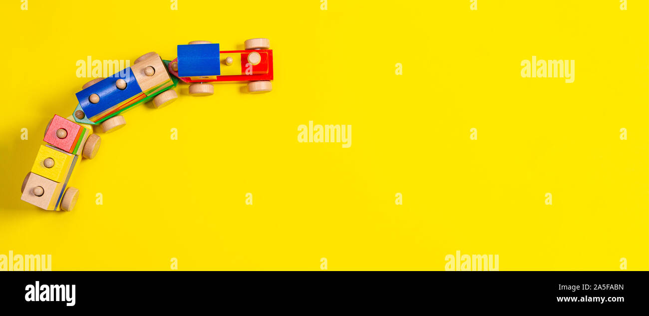 Wooden toy train with colorful blocks on yellow background Stock Photo