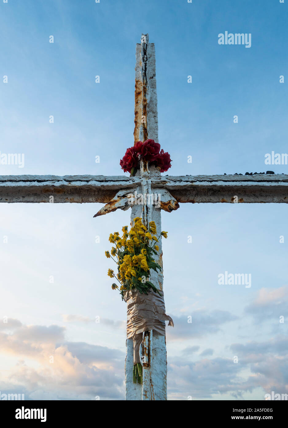 Flowers taped to steel cross on mountain summit. Stock Photo