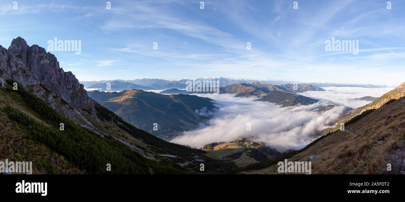After sunrise the fog thickens above the valleys. In the background the peaks of Wiesbachhorn, Kitzsteinhorn and the Großglockner are visible on this Stock Photo