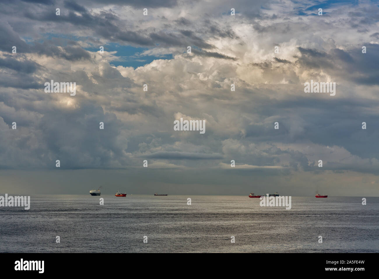 Ships on the roadstead in the open water with dramatic clouds. Livorno, Italy. Stock Photo