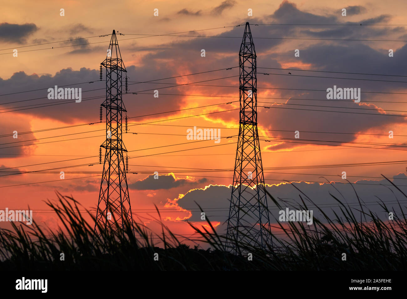 Silhouetted electricity pylons with the vivid sky of sunset Stock Photo ...
