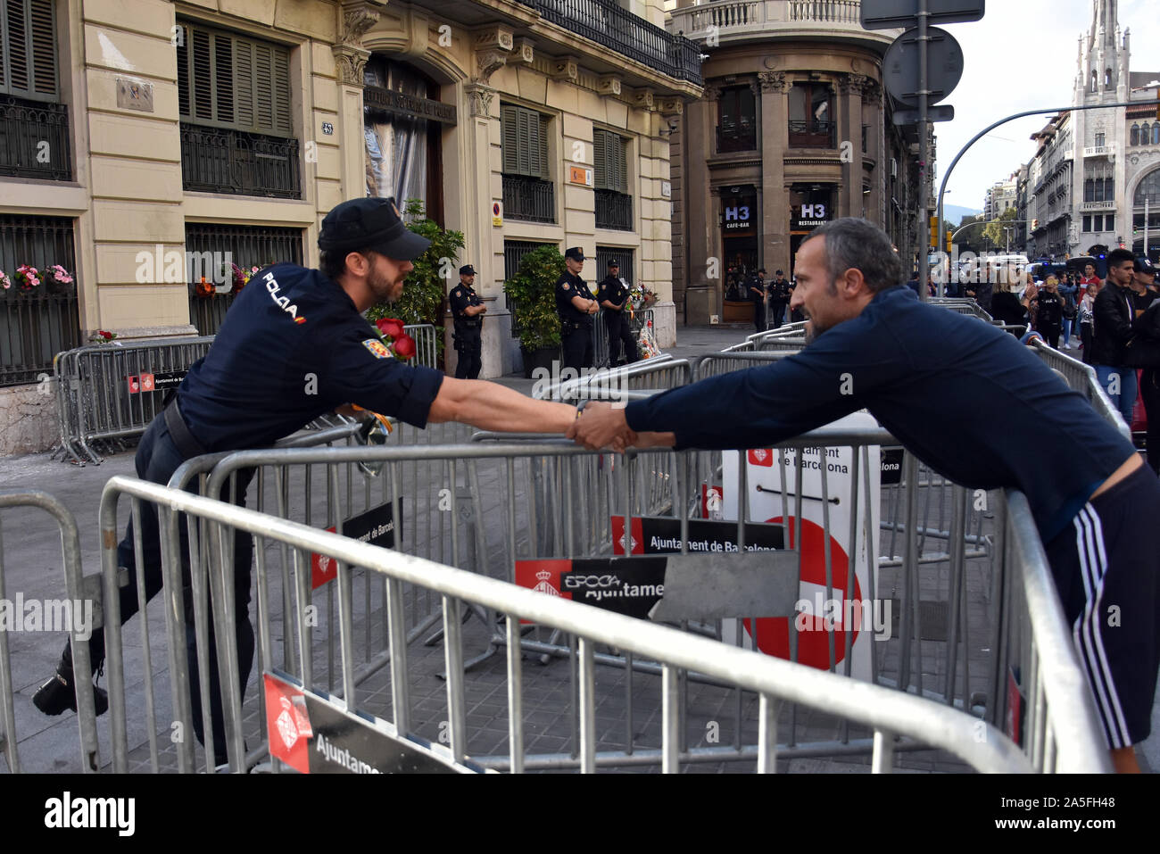 A man shakes hands with a police officer in front of the headquarters of the Spanish police.Several citizens of Barcelona approached the headquarters of the Spanish National Police and offer food, flowers or say hello to them and chant, this is our police 'thanks to the effort they are making to control the demonstrations for the sentence to the political prisoners for the October 1, 2017 referendum. Stock Photo