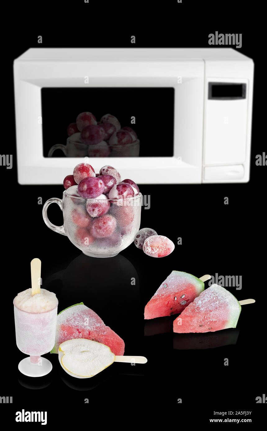 Frozen fruit desserts on a black background and a microwave oven Stock Photo