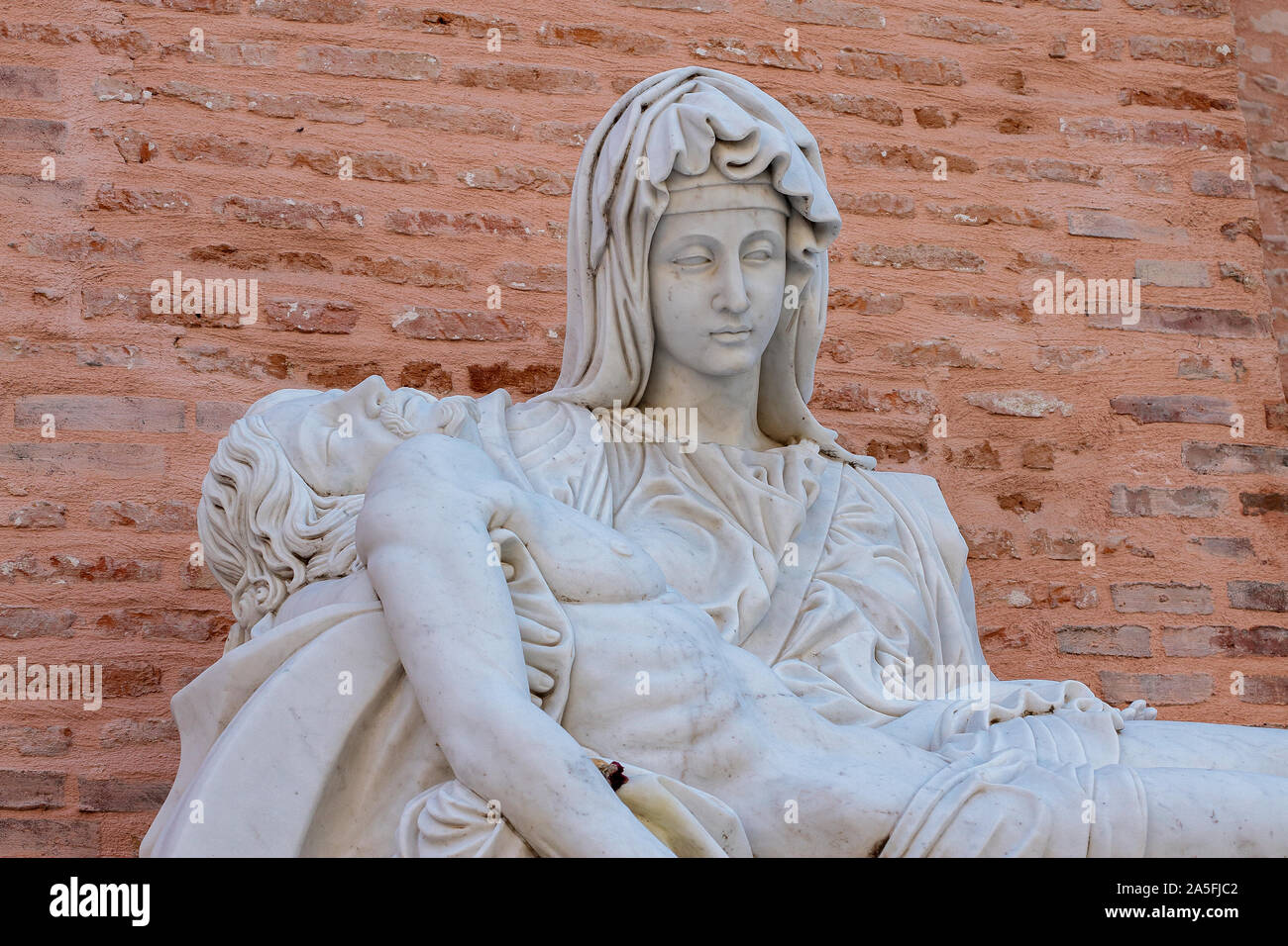 foreground detail of a replica of Miguel Angel´s famous sculpture the Pieta at Adolfo Suarez park of Torrejon de Ardoz, madrid, spain with  wall of br Stock Photo