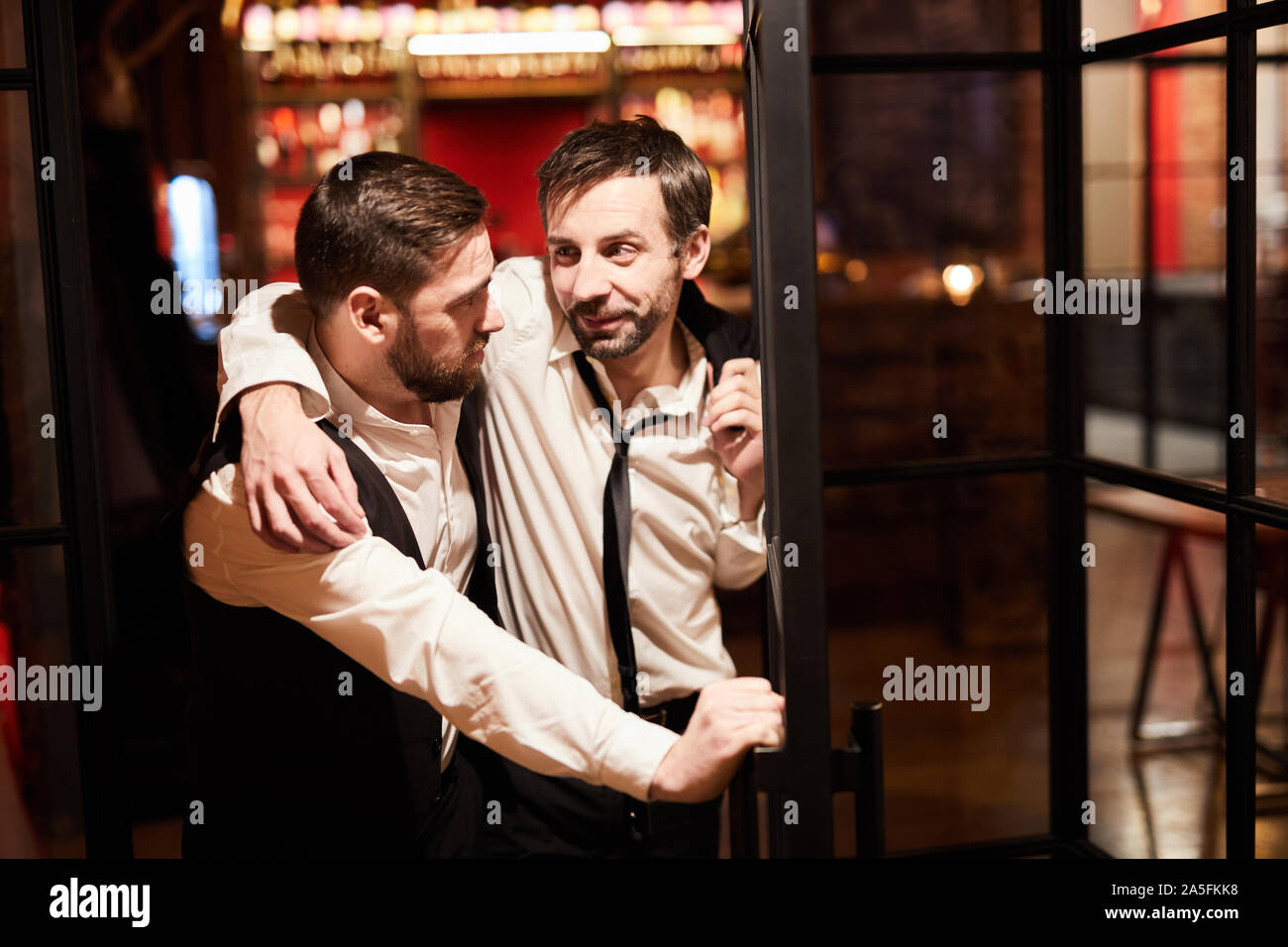 Portrait of wo drunk business men leaving bar late night after work, copy space Stock Photo