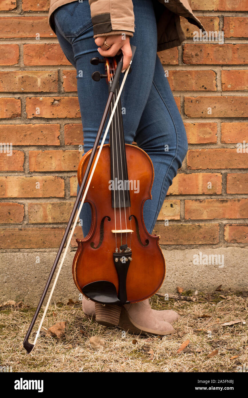 Woman standing outdoors holding a violin and bow Stock Photo