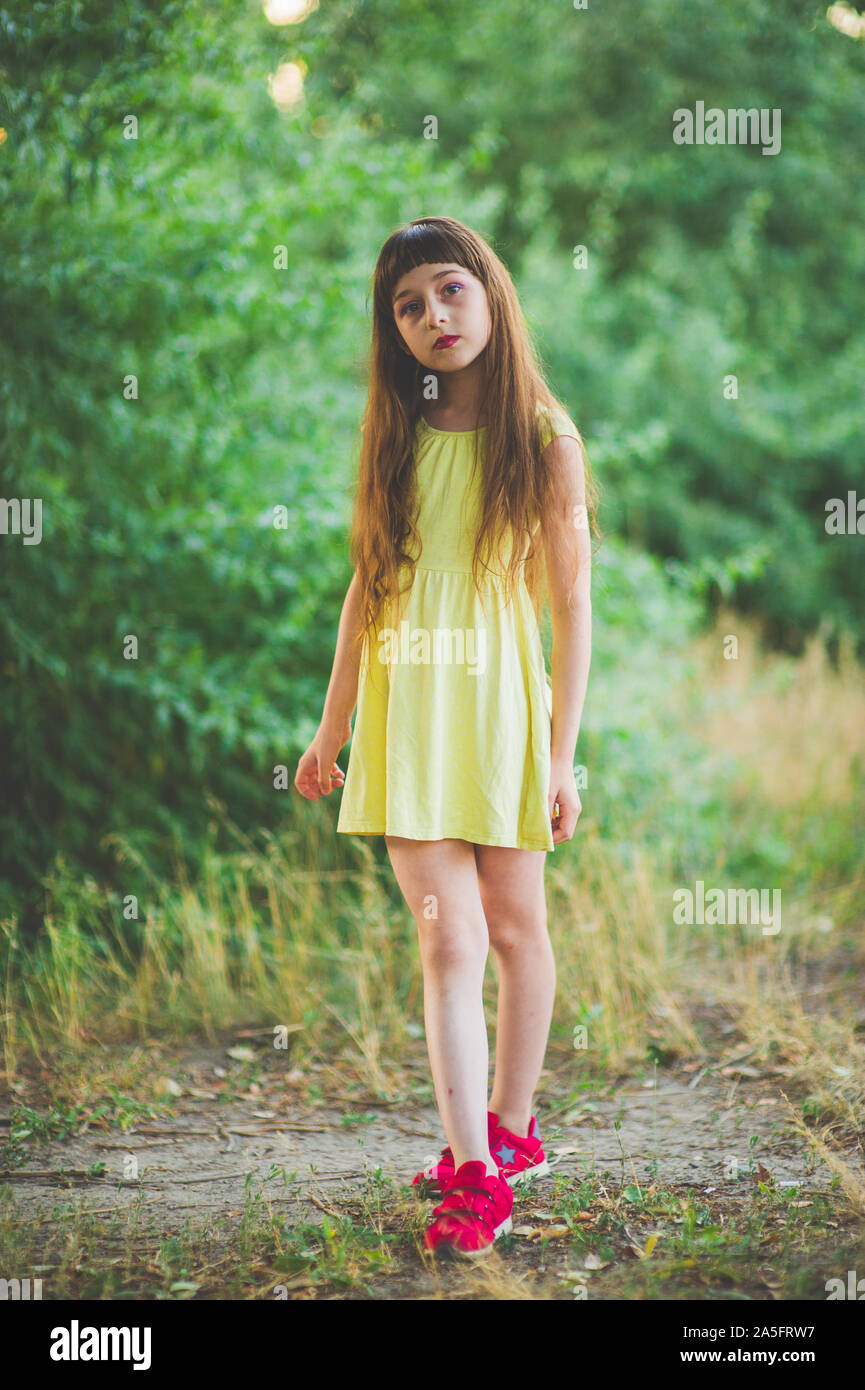 A pretty 9-year-old girl is standing in a field in a rural area on a hot  summer day Stock Photo