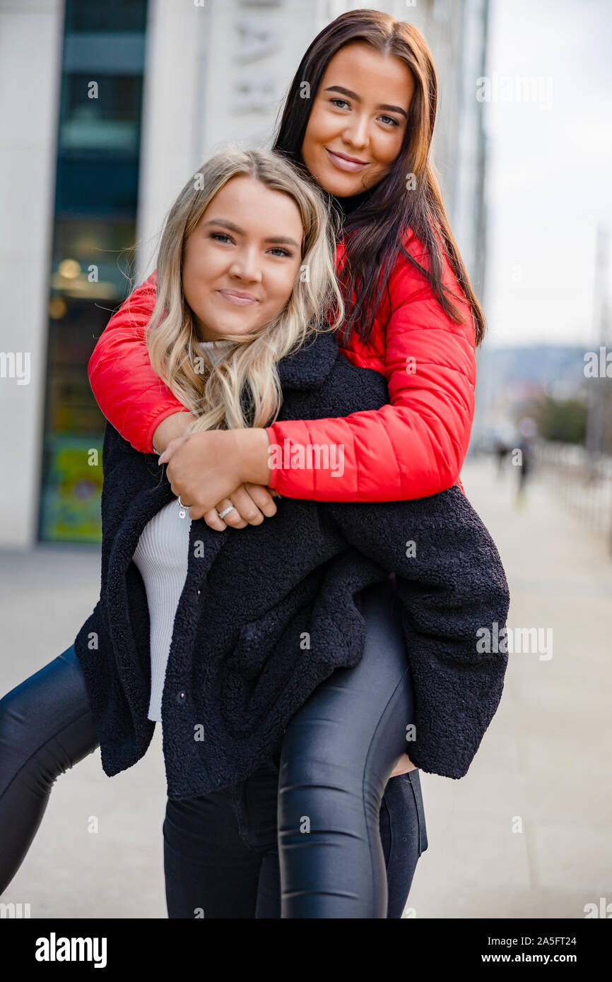 Smiling Woman Piggybacking Female Friend In City Stock Photo