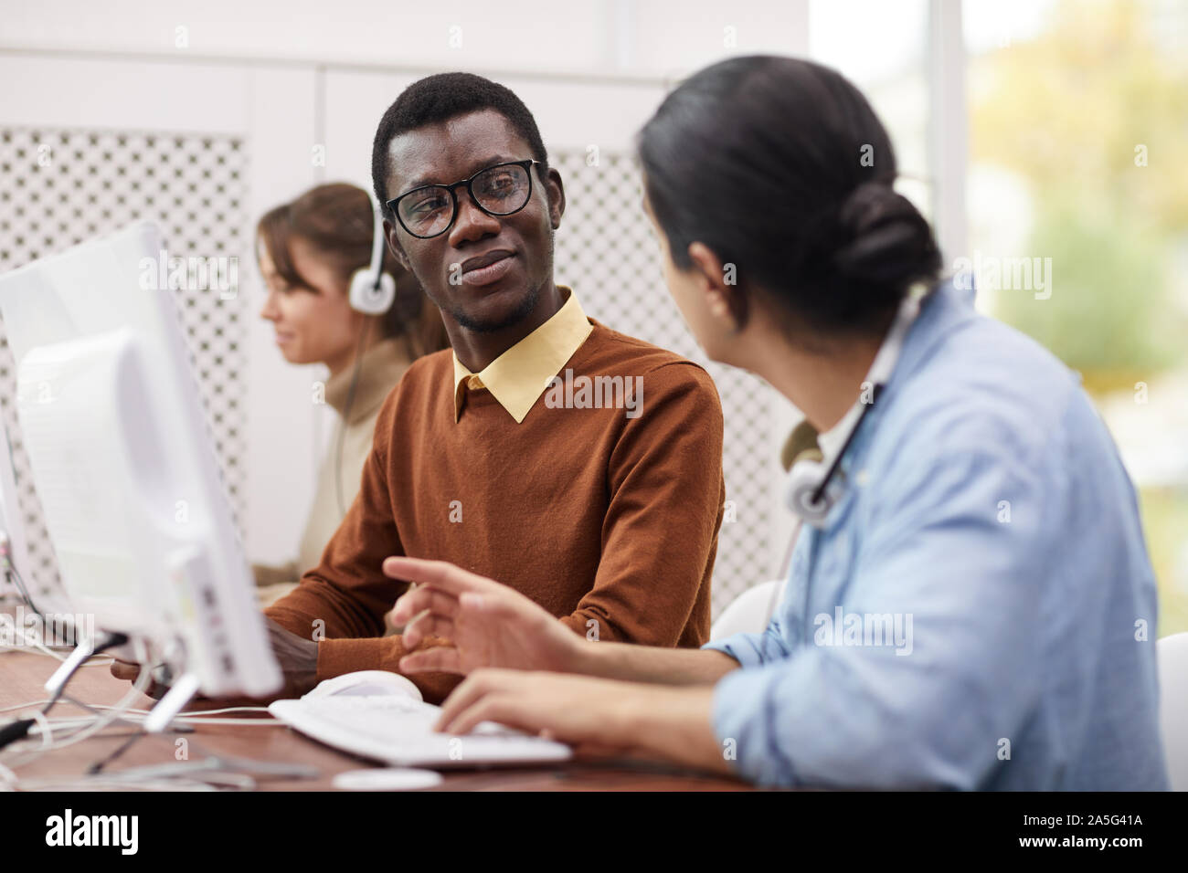 Portrait of African-American student wearing glasses talking to ...