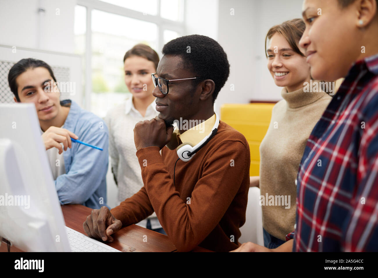 Side view at multi-ethnic group of students using computer while researching for team project in library Stock Photo